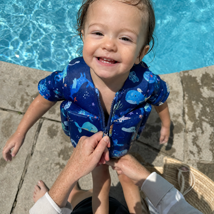 Parent zipping a toddler into an Otterly float suit